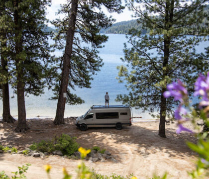 越野车停在湖边，车顶上站着一个人