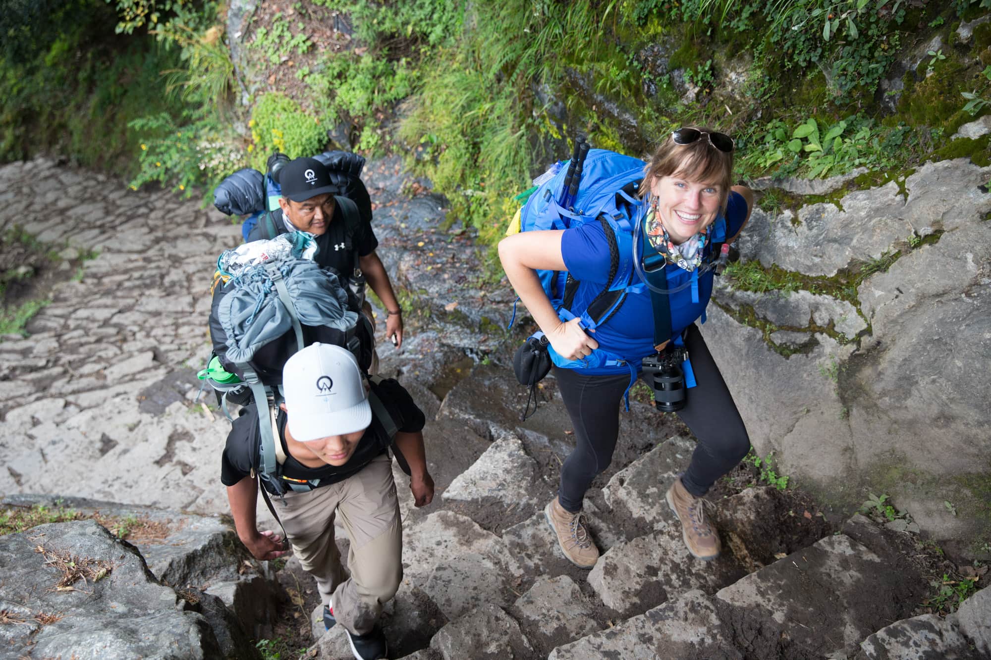 克里斯汀背着背包爬上陡峭的石阶。另外两个背着大背包的徒步旅行者在她身边徒步。