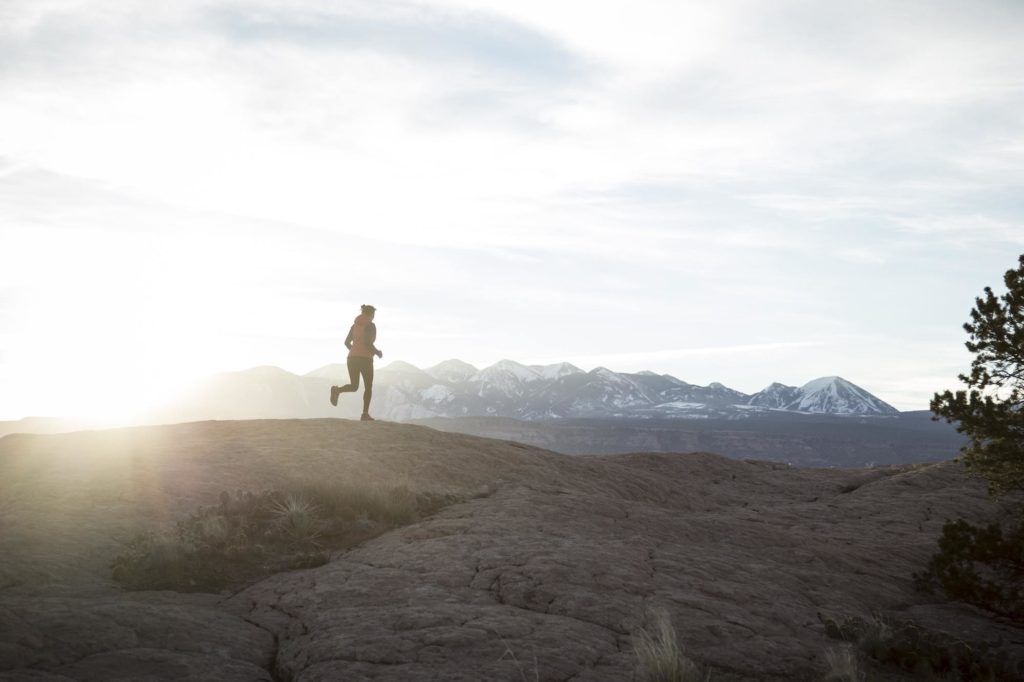 日落时分在山上奔跑的女人//学习如何训练徒步旅行的简单提示和技巧，这样你就可以保持身材，为你的下一次徒步旅行冒险做好准备。