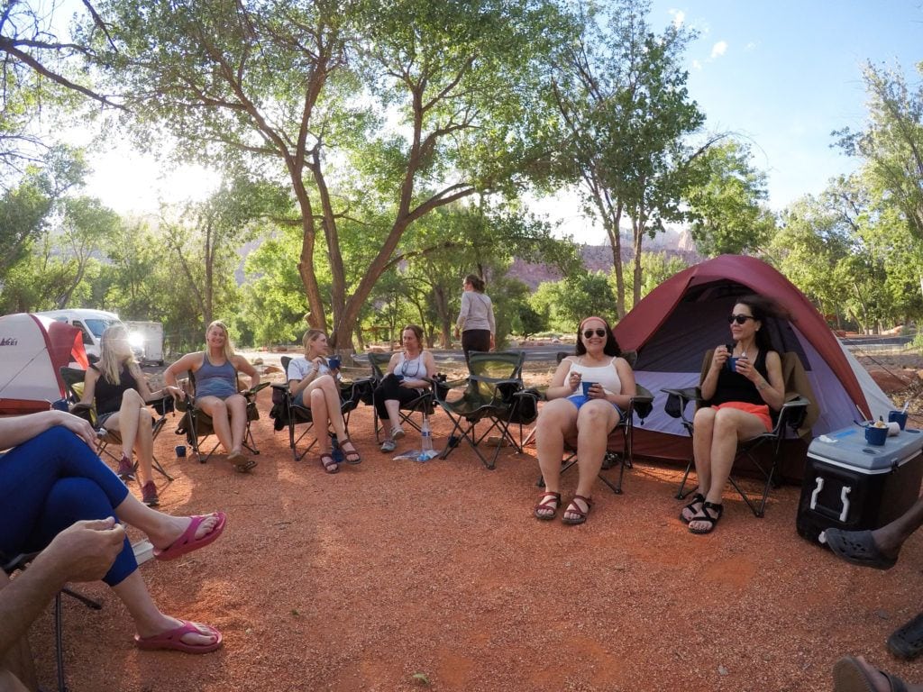 一群人围坐在营地的露营椅上，身后搭着帐篷