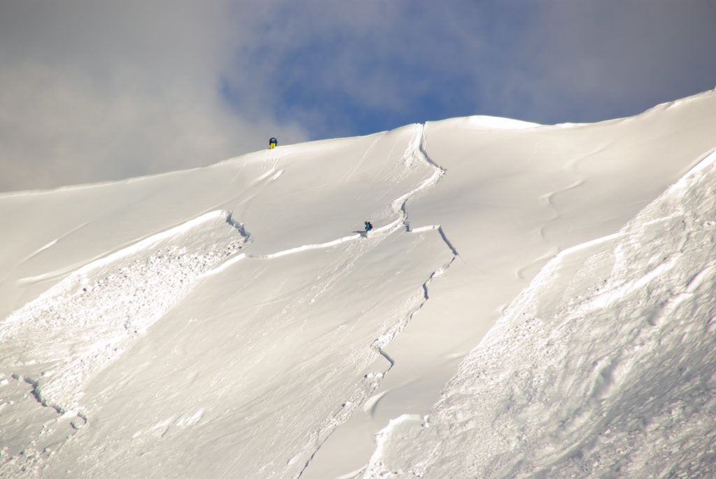 滑雪者在雪崩上方的雪坡上滑雪