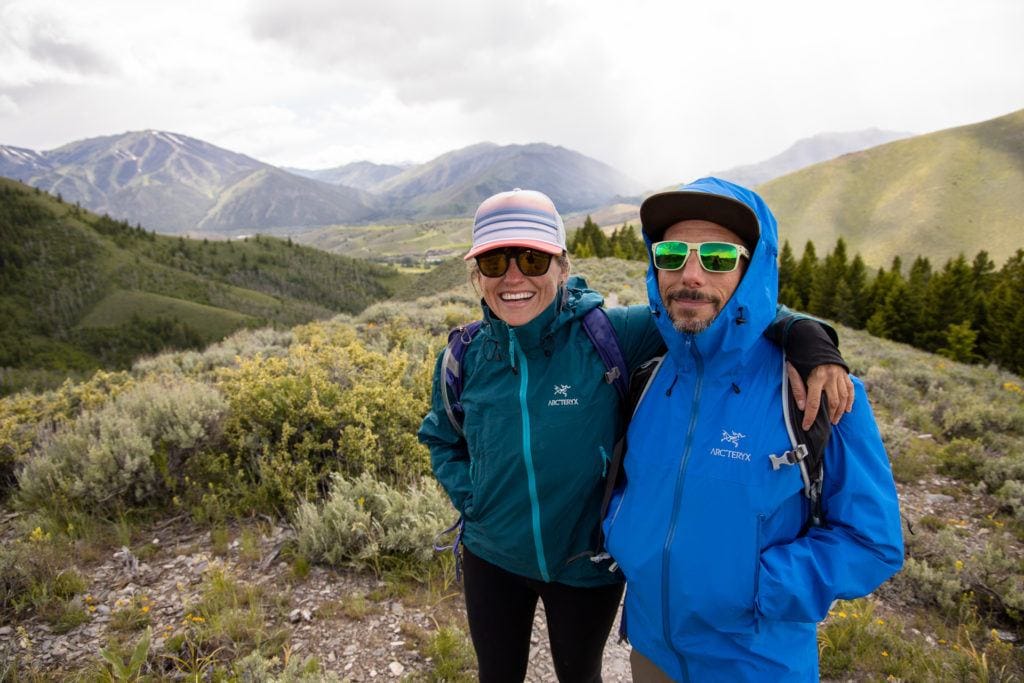woman with her arm around a man smiling while hiking in Arc'teryx rain jackets in the mountains