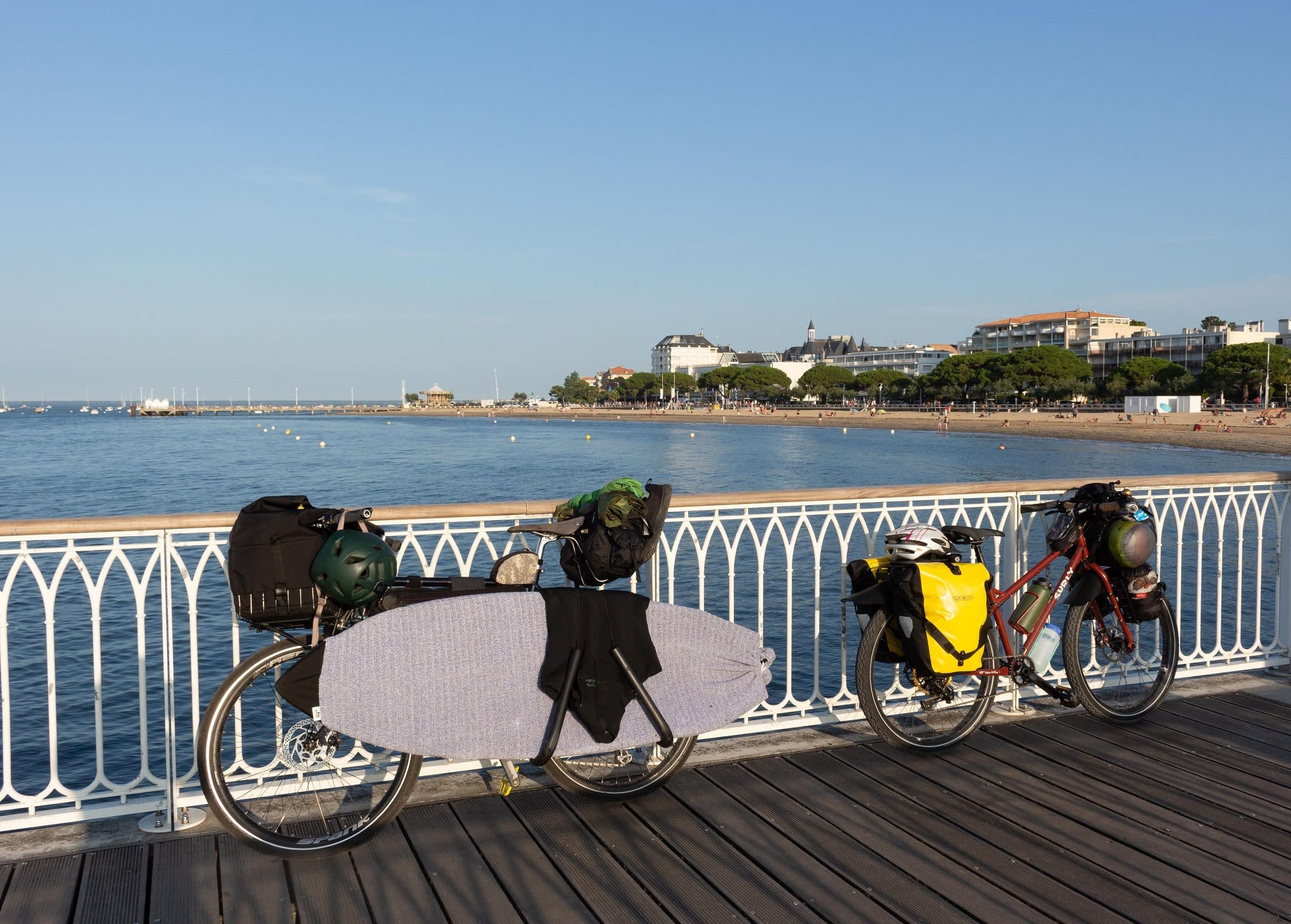 两辆自行车装载自行车旅游装备靠在栏杆与海湾的背景