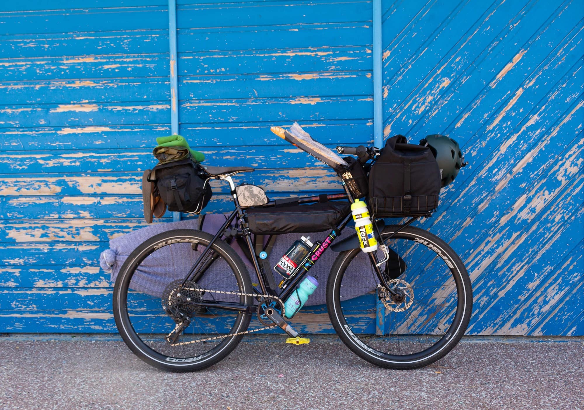 载着包和装备的自行车，靠在蓝色的墙上