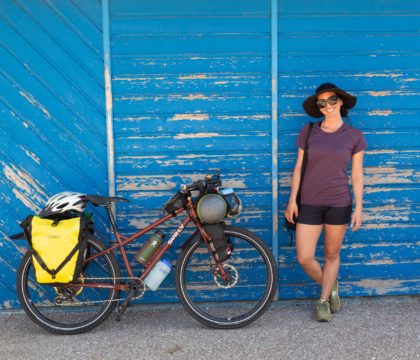 在法国骑自行车旅行时，一名妇女靠在蓝色的墙上