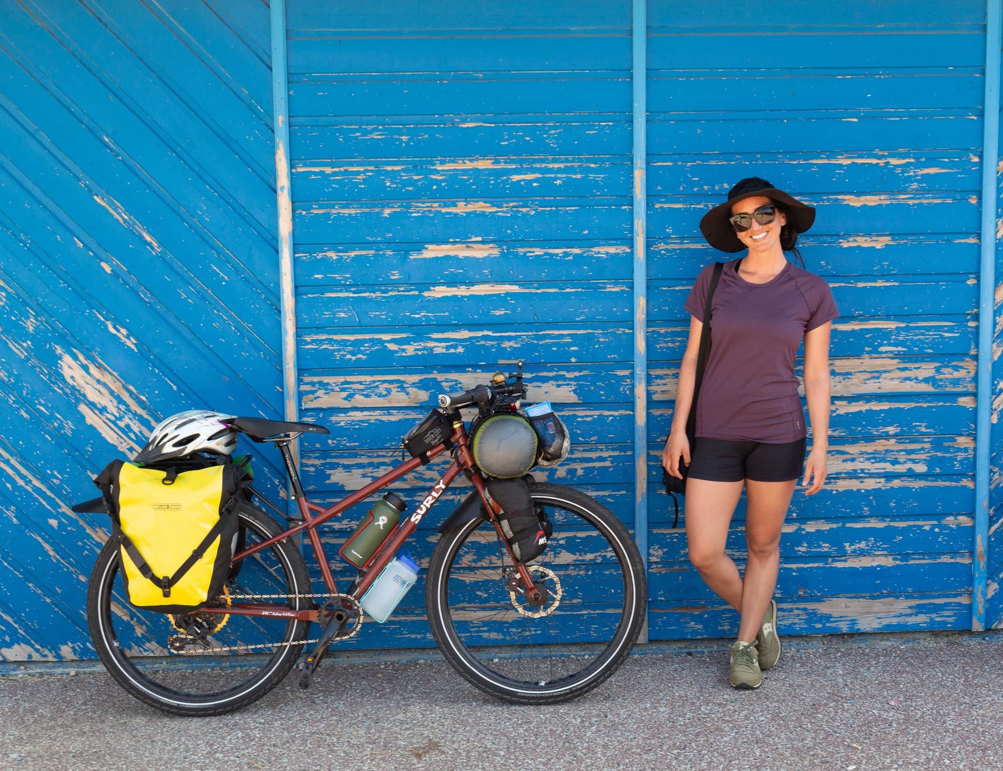 琳达站在装载自行车的自行车旁，在蓝色的漆墙前