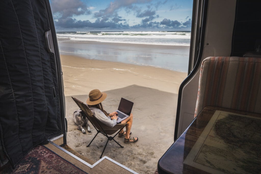 在北卡罗来纳州的海滩上，一名妇女坐在露营椅上用笔记本电脑工作