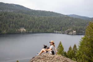 在爱达荷州麦考尔的庞德罗萨州立公园，一名女子坐在一块岩石上俯瞰湖泊