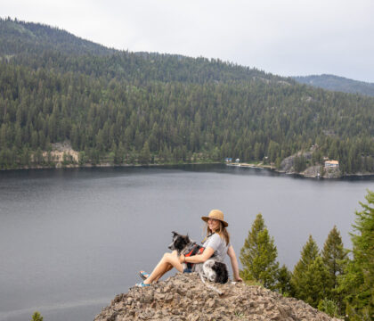 在爱达荷州麦考尔市的庞德罗萨州立公园，一名妇女坐在俯瞰湖泊的岩石上