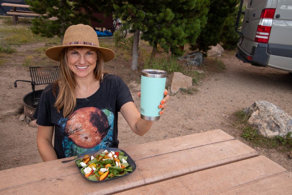 A woman holds the YETI Tumbler on a camping trip
