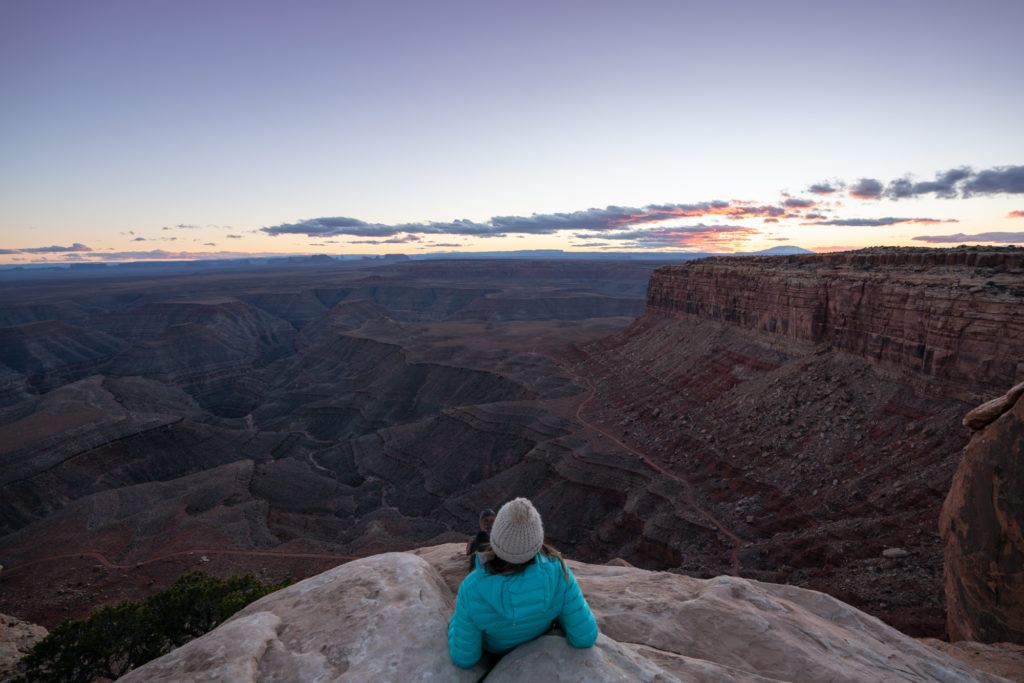 克里斯汀sitting on rock overlook enjoying view out over canyonlands in Utah at dusk