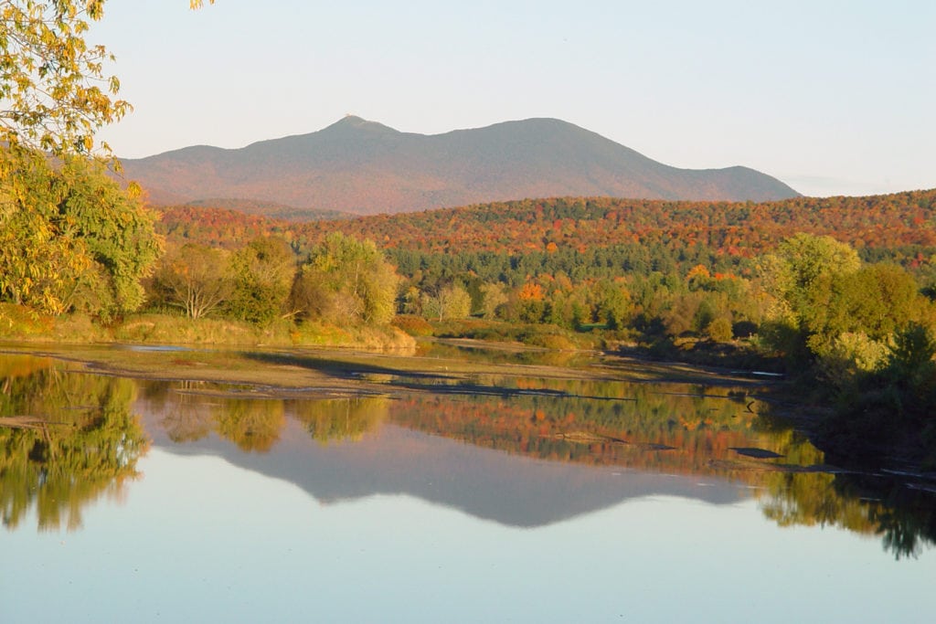 Mountains reflected in water in New England during fall foliage season