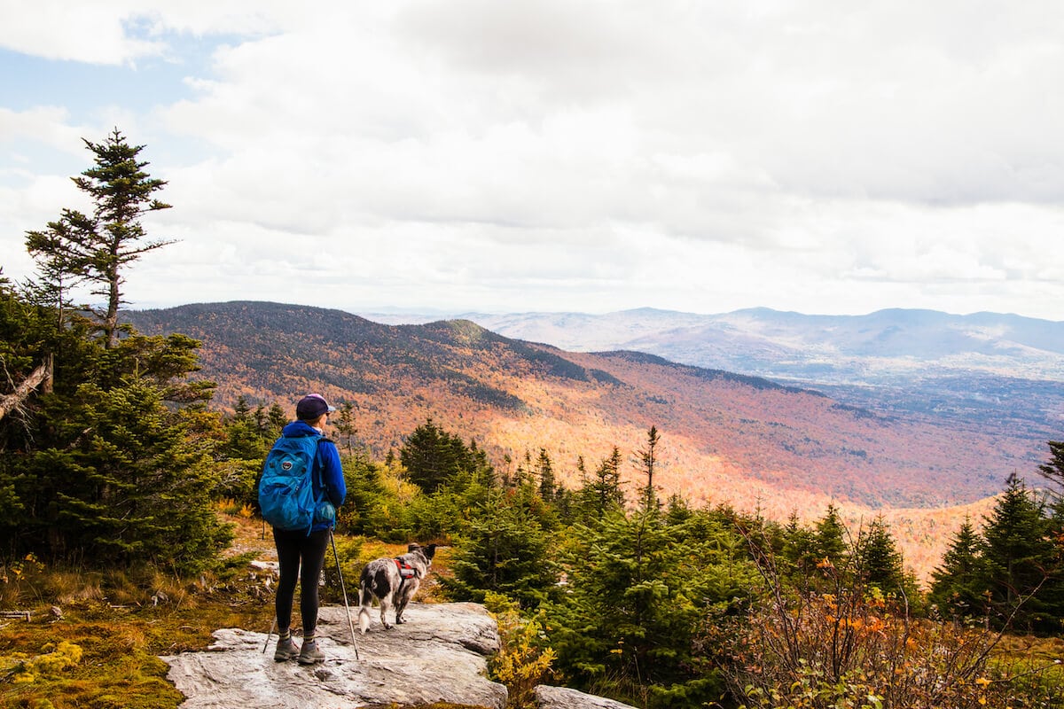 Hiker standing at lookout on hike during fall foliage season in New England