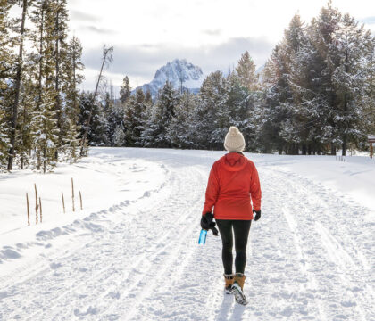妇女徒步旅行在冬天的雪-探索最好的冬季徒步旅行的衣服，基本装备，并提示在寒冷的天气分层