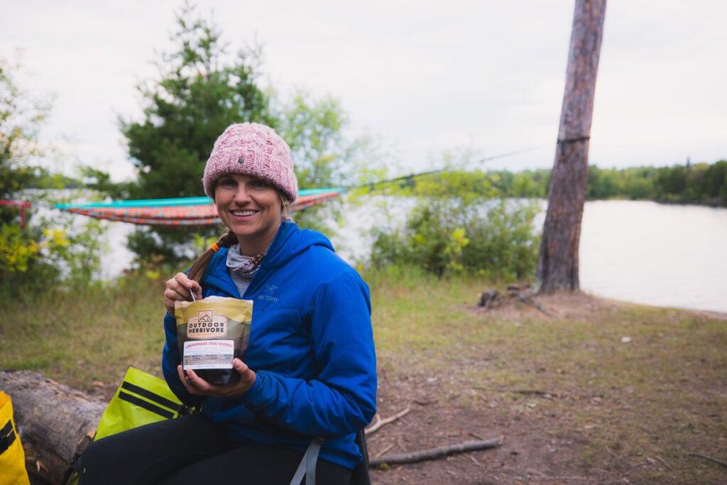 A woman eats an Outdoor Omnivore backpacking meal in the Minnesota Boundary waters