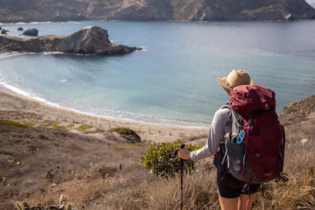 A woman looks over the bay on the Trans-Catalina Trail in California. She has the Dueter Aircontact Lite backpack on