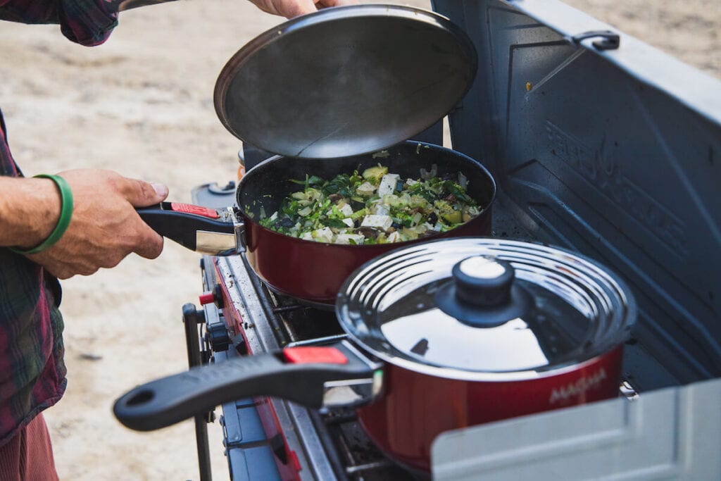 A man uses Magma Cookware on a camp stove