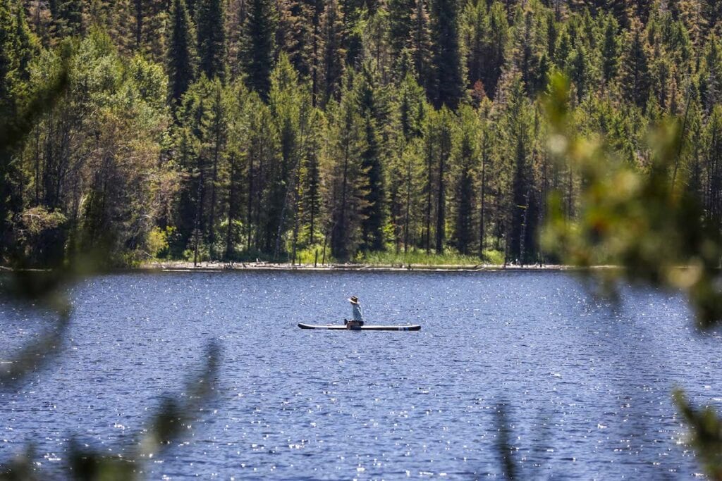 一名女子跪在湖上的桨板上