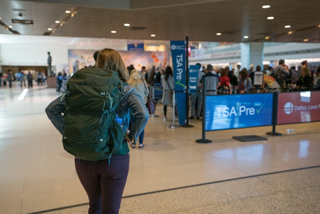 克里斯汀背着背包在机场//为户外爱好者提供礼物的终极指南，为远足者，背包客，露营者，旅行者，滑雪者，户外宠物等提供想法。