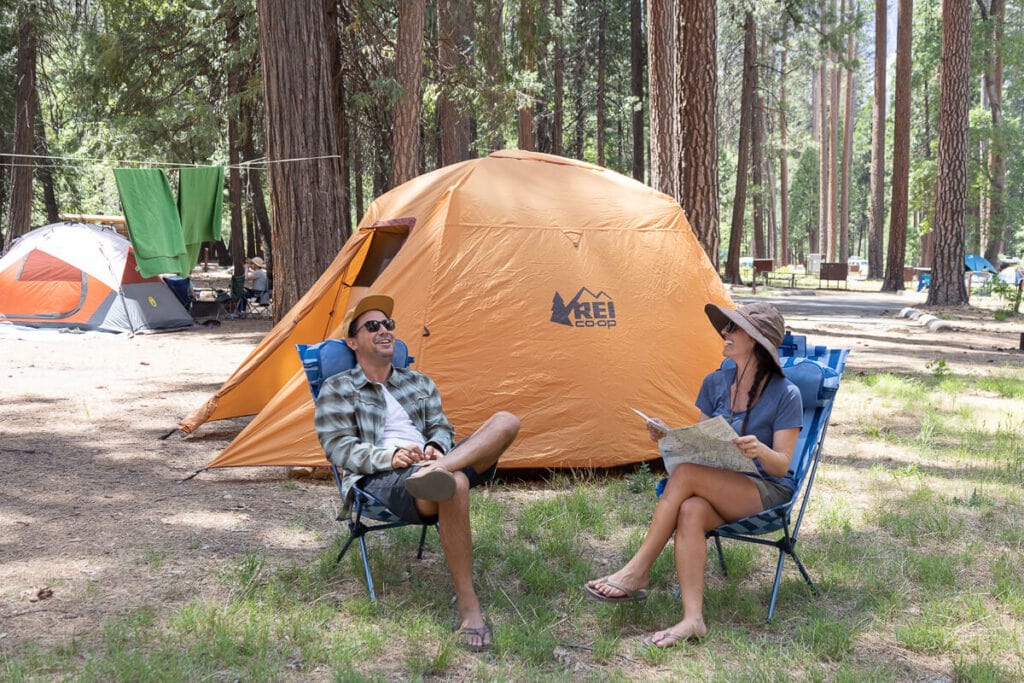 两个人坐在REI帐篷前的Helinox日落露营椅上