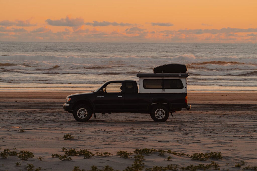 日落时分沙滩上的卡车露营车