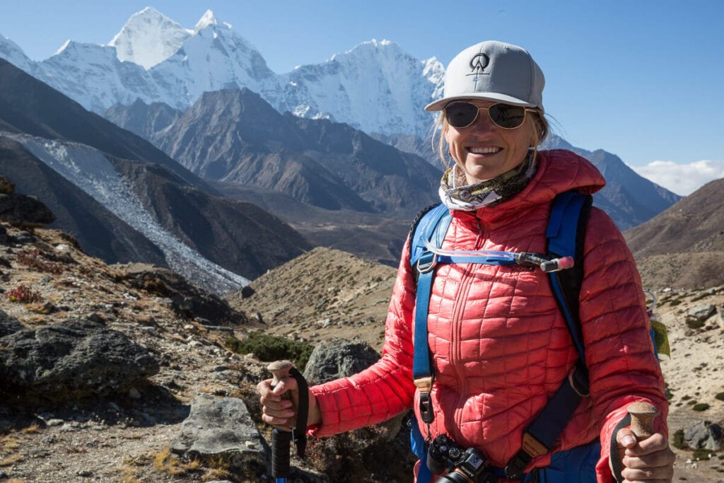 一名身穿粉色NorthFace Thermoball保温卫衣的女子在珠峰大本营徒步旅行中微笑
