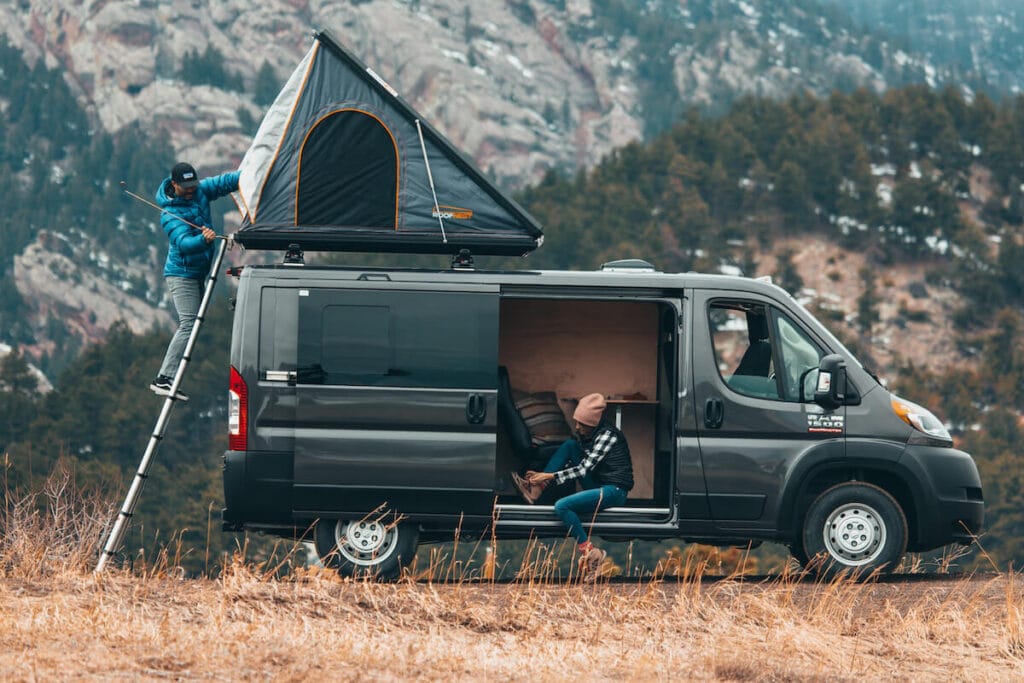 A Dodge Promaster rental campervan from Native Campervans with a rooftop tent being set up for camp