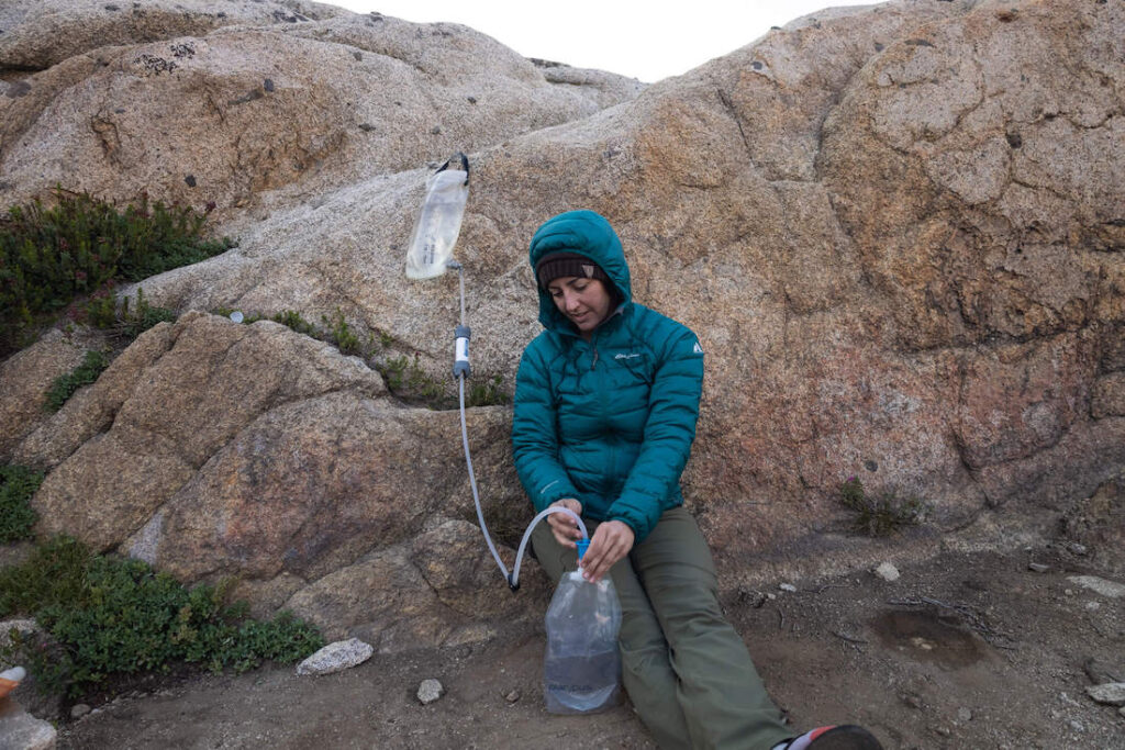 A woman using the Platypus gravity works to filter water on a backpacking trip