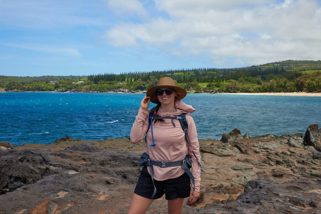 A woman wears a pink REI Co-op Sahara Shade Hoodie while hiking in Maui