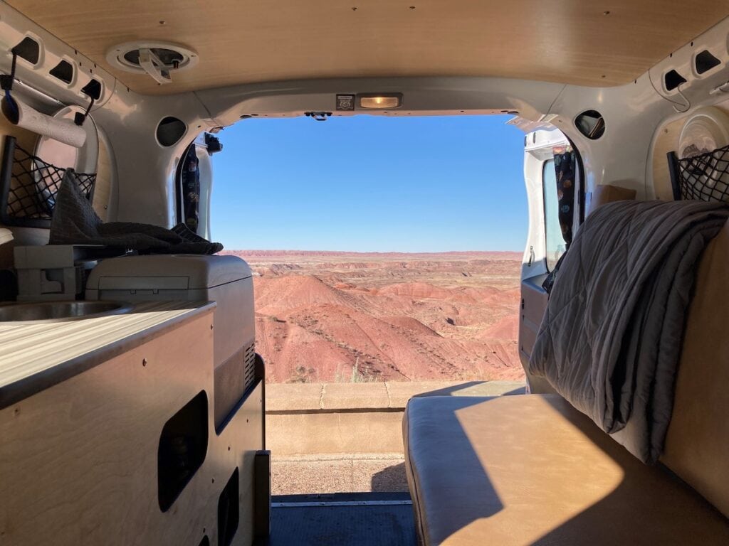 Interior view of a Vander rental campervan looking out the back doors at a desert scene