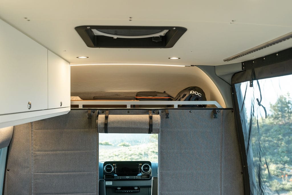 在一辆由Outside Van改装的Sprinter Van中，超过驾驶室存储和绝缘窗帘