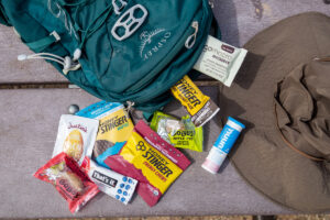 A hiking daypack filled with hiking snacks: Honey Stinger, Justin's nut butter, Go Macro bars, Nuun tablets, and other snacks.