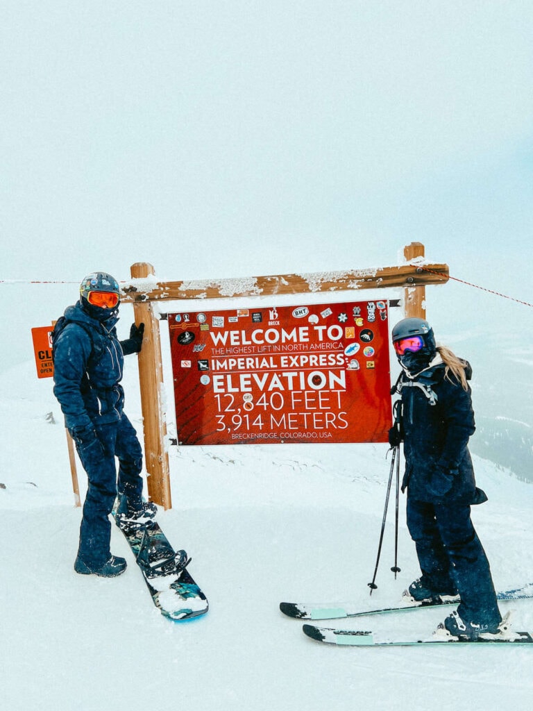 科罗拉多州布雷肯里奇滑雪场，滑雪者和滑雪板站在标志前，上面写着帝国快车缆车是北美最高的缆车，海拔12840英尺