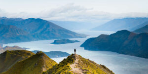 一名男子站在新西兰南岛的罗伊斯峰观景台，可以欣赏到峡湾和山脉的壮丽景色