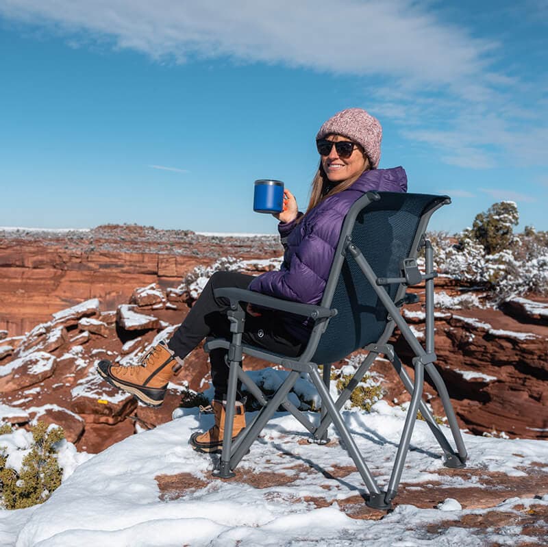 在风景秀丽的犹他州沙漠，地上有雪，坐在雪人步道营地椅子上的女人