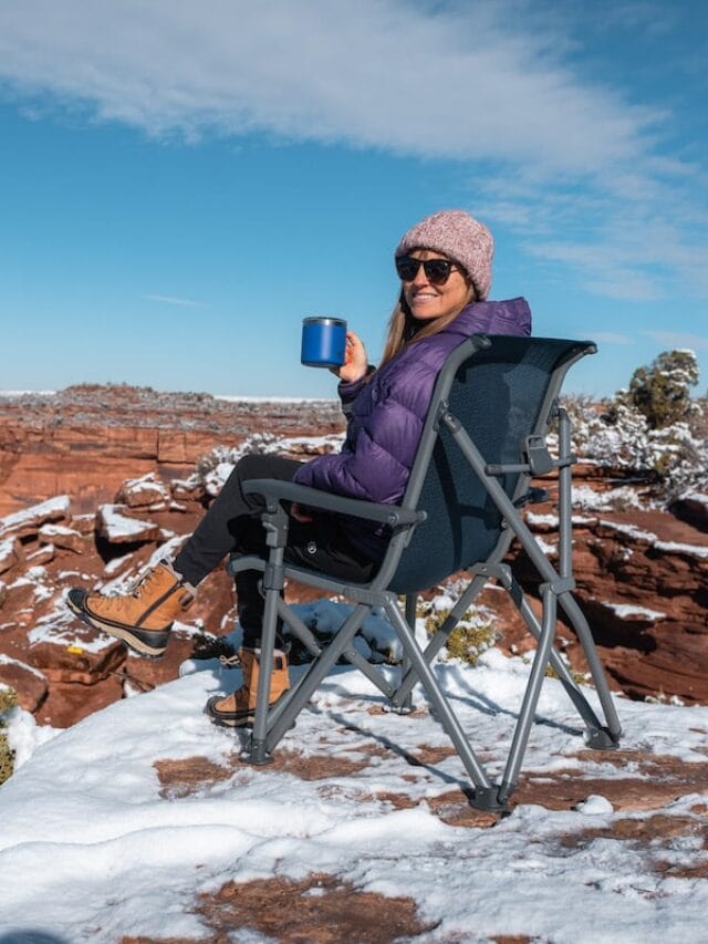 女子坐在雪人步道的营地椅子上，在一个雪景，在犹他州的红岩位置