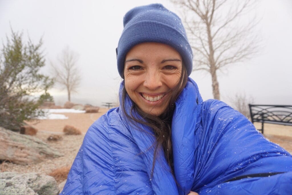 在小雪飘落期间，一名女子在户外生命峰会的睡袋里自拍