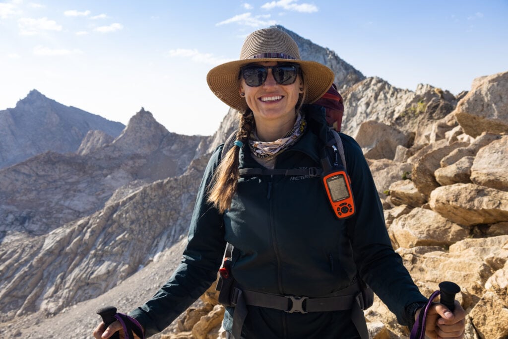 Kristen smiling for photo on high alpine trail in Sequoia National Park in California wearing backpacking gear and Wallaroo sun hat