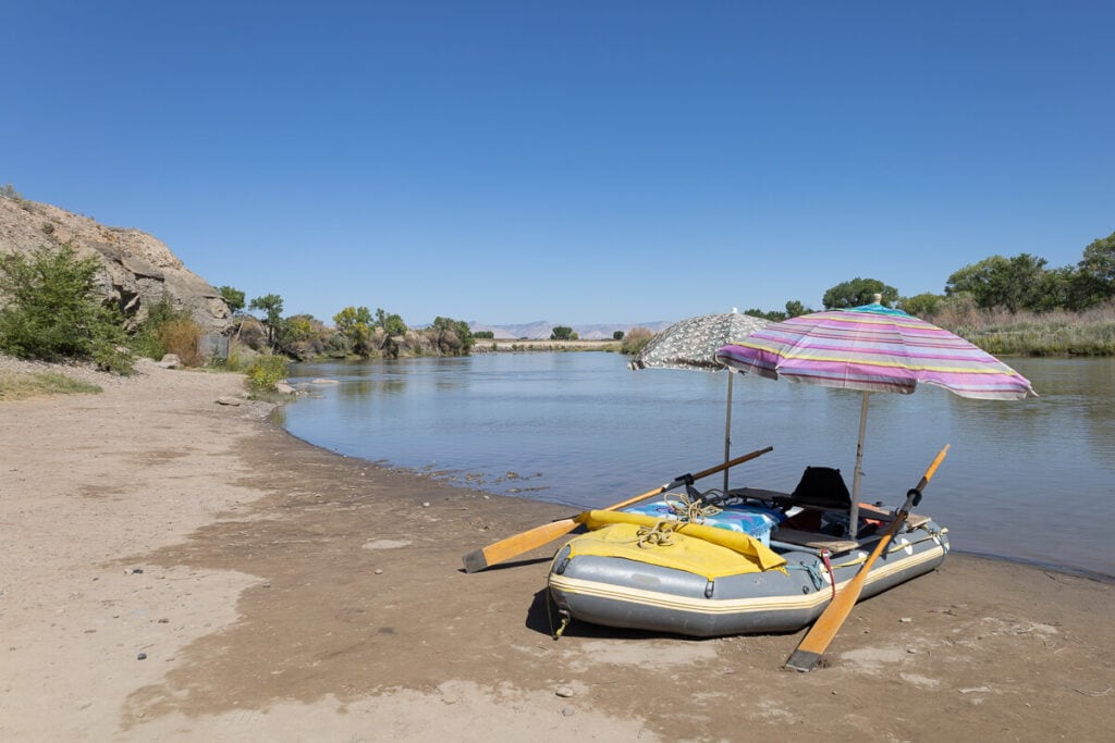 在科罗拉多河的海滩上，装满了装备和遮阳伞的木筏停了下来