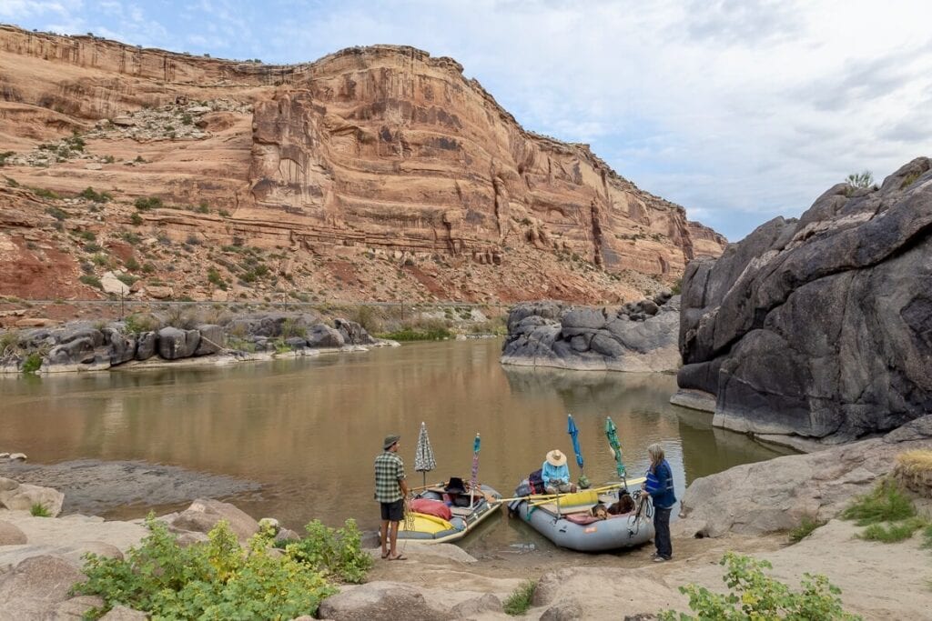 Two packrafts pulled up on small beach with people unloading gear on Colorado River in Utah