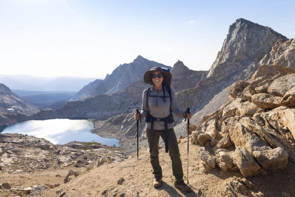 Backpacker standing for photo with alpine lake behind her in Sequoia National Park in California