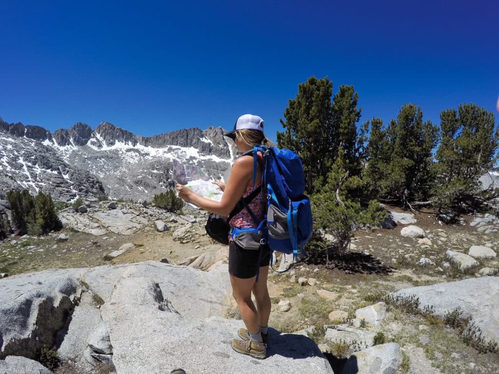 Girl on a backpacking trip in Kings Canyon National Park in Dusy Basin holding a trail map