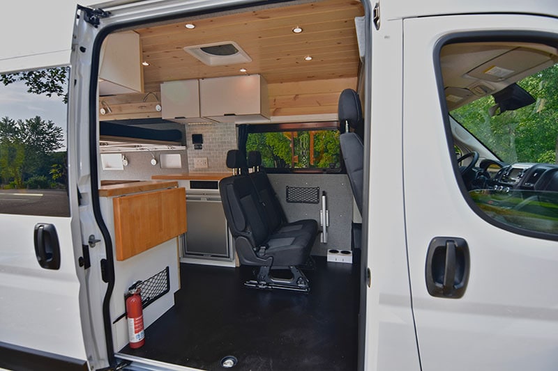Interior of a rental campervan from Voyager Vampervans through the sliding door showing two passenger seats and a kitchen with a fridge and cabinets